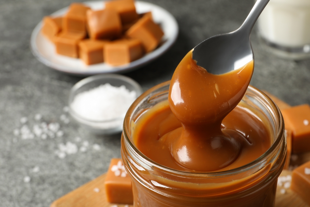 Taking,Yummy,Salted,Caramel,With,Spoon,From,Glass,Jar,At