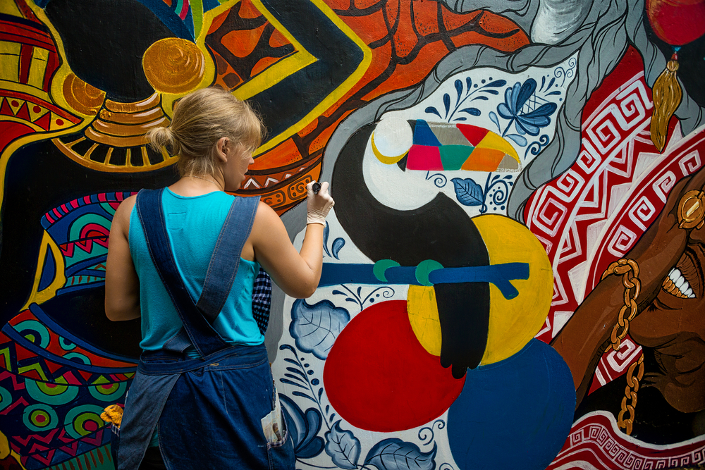 Cheerful,Young,Woman,Painting,On,The,Wall