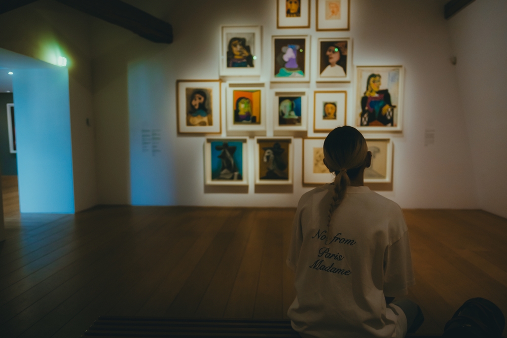 A,Woman,Observing,A,Collection,Of,Vibrant,Framed,Portraits,In